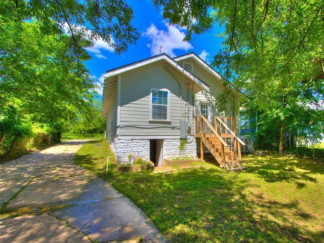 1017 N Broadway Ave, Shawnee, OK 74801 - back of property with concrete driveway, a lawn, stairway, and stone siding