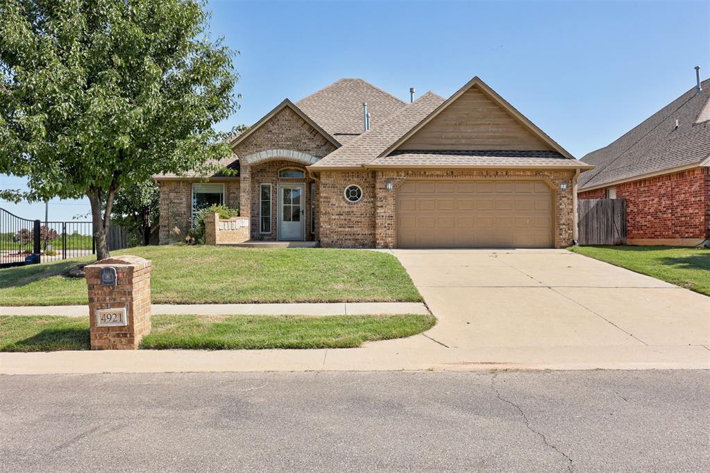 4921 SW 120th Ter, Oklahoma City, OK 73173 - view of front of property with a garage, driveway, brick siding, and roof with shingles