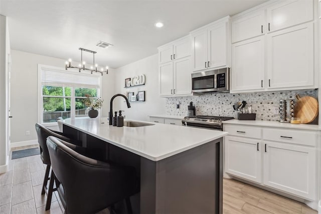 124 W 5th St, Arcadia, OK 73007 - kitchen featuring stainless steel microwave, decorative backsplash, white cabinets, light countertops, and an island with sink