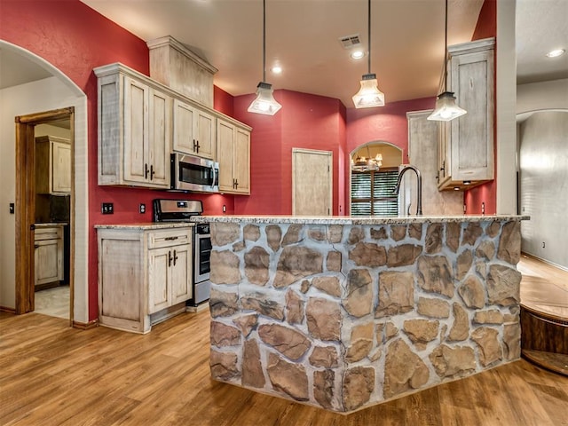 3501 Shell Ln, Yukon, OK 73099 - kitchen featuring stainless steel appliances, light wood-style floors, pendant lighting, arched walkways, and a peninsula