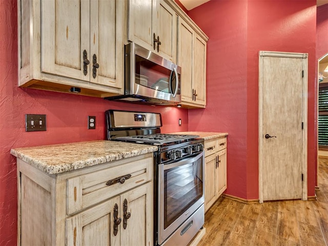3501 Shell Ln, Yukon, OK 73099 - kitchen with appliances with stainless steel finishes, light wood-style flooring, a textured wall, light stone countertops, and baseboards