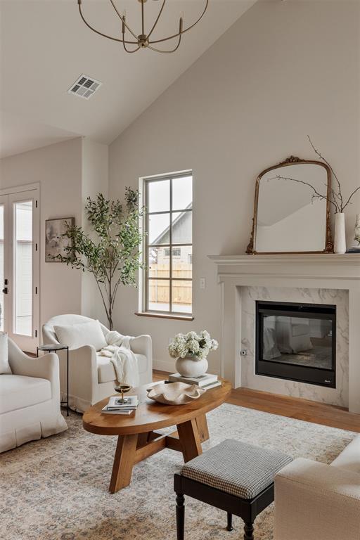 2917 Kite Tail Xing, Edmond, OK 73034 - living room featuring a chandelier, plenty of natural light, a fireplace, wood finished floors, and high vaulted ceiling