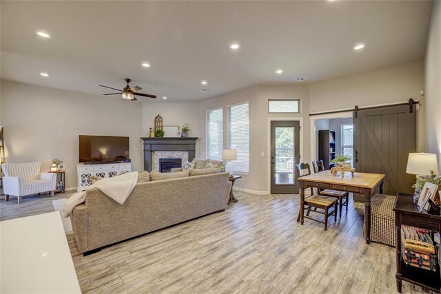 2613 Ethan Ln, Oklahoma City, OK 73160 - living area with light wood-style floors, a barn door, ceiling fan, recessed lighting, and a stone fireplace