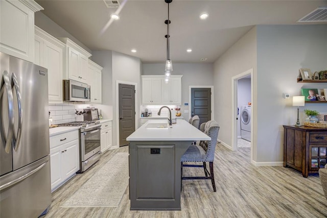 2613 Ethan Ln, Oklahoma City, OK 73160 - kitchen with stainless steel appliances, a sink, separate washer and dryer, light wood-style flooring, and decorative backsplash