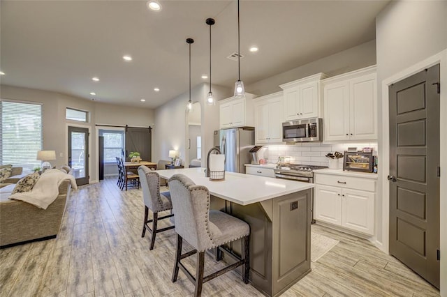 2613 Ethan Ln, Oklahoma City, OK 73160 - kitchen with stainless steel appliances, open floor plan, a kitchen bar, an island with sink, and tasteful backsplash