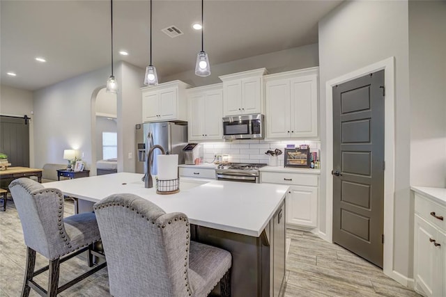 2613 Ethan Ln, Oklahoma City, OK 73160 - kitchen with appliances with stainless steel finishes, a breakfast bar area, a kitchen island with sink, light wood-type flooring, and white cabinets