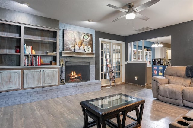9703 Woodrock Ct, Oklahoma City, OK 73130 - living room featuring wood finished floors, a ceiling fan, a brick fireplace, and a chandelier