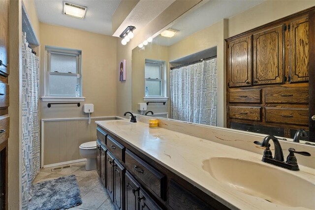 9703 Woodrock Ct, Oklahoma City, OK 73130 - bathroom with double vanity, tile patterned flooring, wainscoting, and a shower with curtain