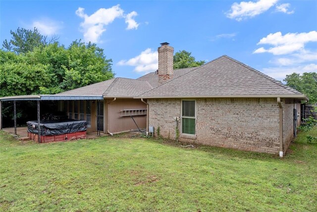 9703 Woodrock Ct, Oklahoma City, OK 73130 - rear view of house featuring a hot tub, a chimney, a yard, brick siding, and a shingled roof