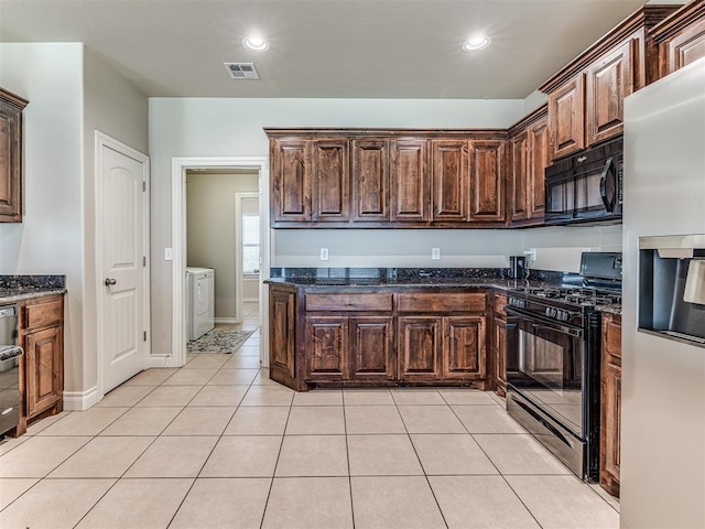 1861 Debbie Dr, Guthrie, OK 73044 - kitchen featuring black appliances, washing machine and dryer, dark stone countertops, light tile patterned flooring, and dark brown cabinetry