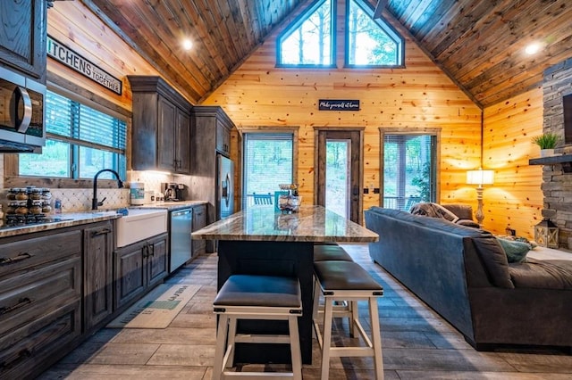 193 Pine Forest Trl, Broken Bow, OK 74728 - kitchen with open floor plan, stainless steel appliances, wooden ceiling, a breakfast bar area, and wood walls