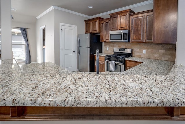 7521 Prairie Twyne Dr, Yukon, OK 73099 - kitchen featuring stainless steel appliances, tasteful backsplash, light stone countertops, crown molding, and a peninsula