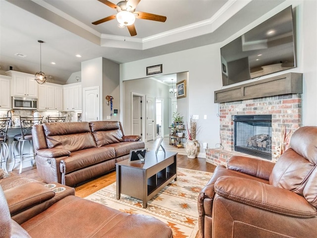 11728 SW 15th Ter, Yukon, OK 73099 - living room featuring a raised ceiling, light wood-style flooring, ceiling fan, recessed lighting, and ornamental molding