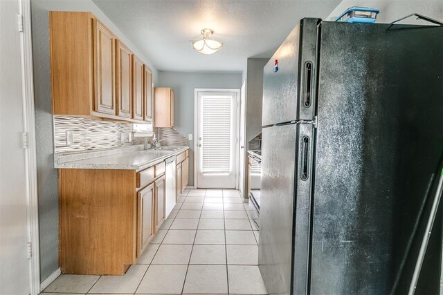 1705 NW 147th St, Edmond, OK 73013 - kitchen with freestanding refrigerator, light tile patterned floors, light countertops, decorative backsplash, and a sink