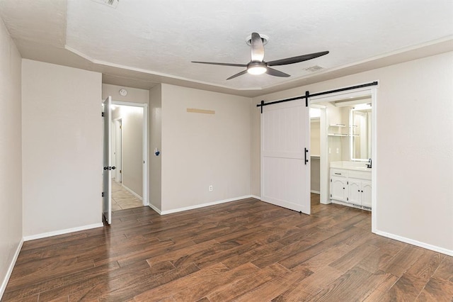 2232 Butternut Pl, Edmond, OK 73013 - unfurnished bedroom featuring a barn door, wood finished floors, baseboards, and ceiling fan