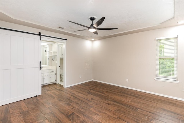 2232 Butternut Pl, Edmond, OK 73013 - unfurnished bedroom featuring a barn door, baseboards, dark wood-type flooring, and connected bathroom