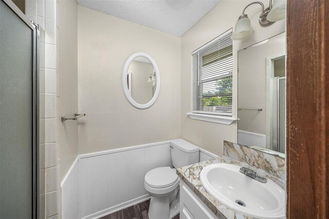 7506 NW Welco Ave, Lawton, OK 73505 - full bath with a wainscoted wall, toilet, wood finished floors, a shower stall, and a textured ceiling