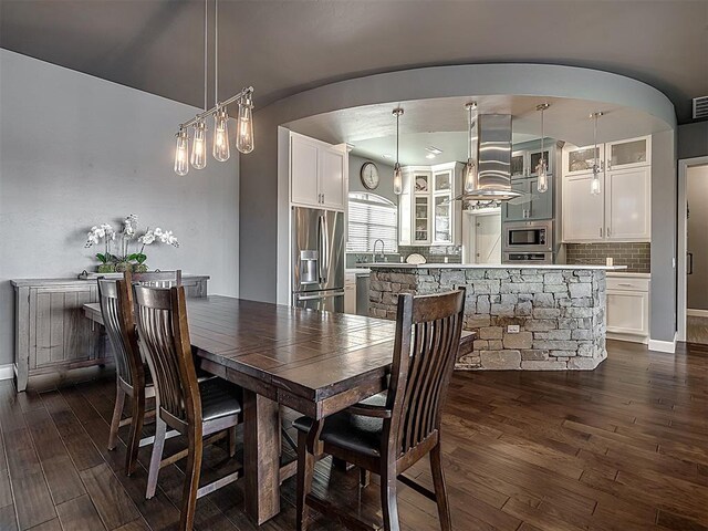 15321 Salem Creek Pl, Edmond, OK 73013 - dining area with arched walkways, dark wood finished floors, and baseboards