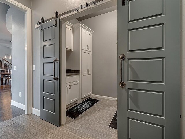 15321 Salem Creek Pl, Edmond, OK 73013 - mudroom featuring a barn door, light wood-style flooring, and baseboards