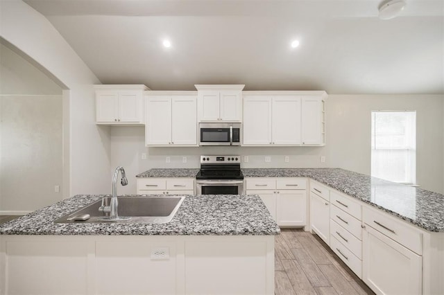 6100 SE 7th St, Midwest City, OK 73110 - kitchen featuring appliances with stainless steel finishes, a sink, a peninsula, white cabinetry, and vaulted ceiling