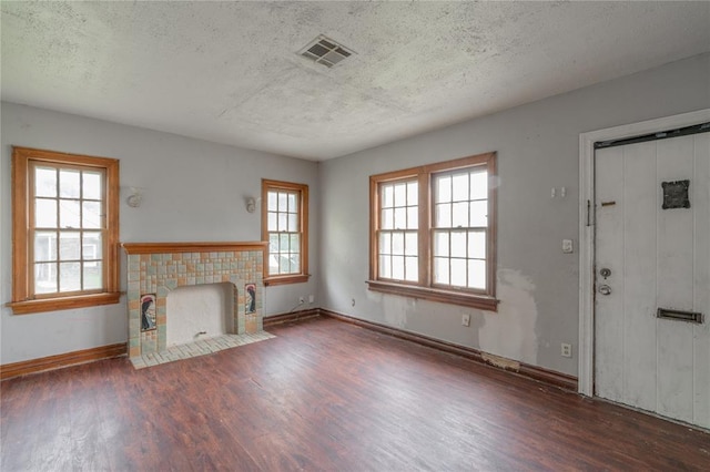 2325 E Madison St, Oklahoma City, OK 73111 - unfurnished living room with wood finished floors, a textured ceiling, and a tile fireplace