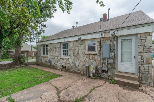 2325 E Madison St, Oklahoma City, OK 73111 - back of house with stone siding, roof with shingles, and a lawn