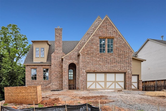 7524 Walk In The Park Dr, Edmond, OK 73034 - english style home with an attached garage, brick siding, and a chimney