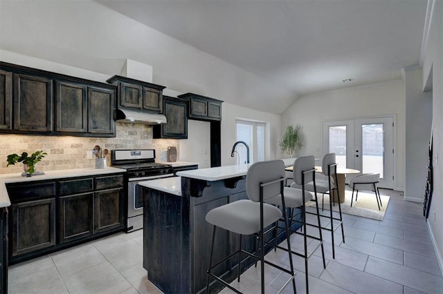 4116 NW 155th St, Edmond, OK 73013 - kitchen featuring stainless steel range with gas stovetop, tasteful backsplash, light tile patterned floors, a kitchen bar, and light countertops