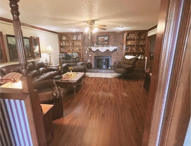 12301 US Highway 77, Lexington, OK 73051 - living area featuring built in shelves, a brick fireplace, wood finished floors, a textured ceiling, and ceiling fan