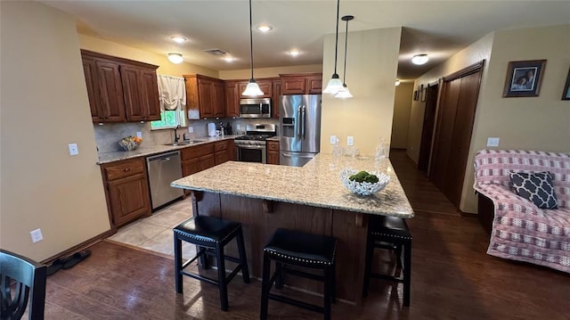 339770 E 1040th Cir, Meeker, OK 74855 - kitchen with stainless steel appliances, a peninsula, a kitchen bar, light stone countertops, and decorative light fixtures