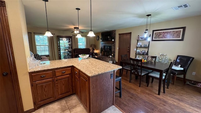339770 E 1040th Cir, Meeker, OK 74855 - kitchen featuring a peninsula, ceiling fan, light stone countertops, a breakfast bar, and decorative light fixtures