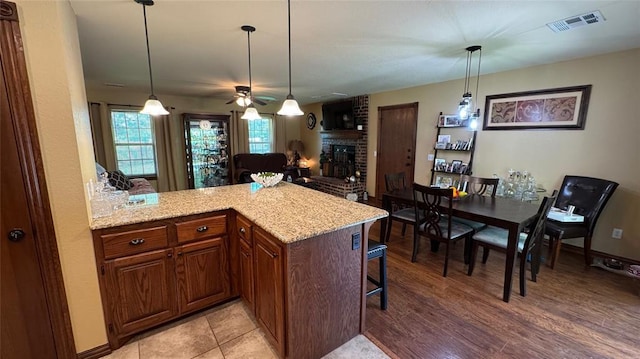 339770 E 1040th Cir, Meeker, OK 74855 - kitchen with a ceiling fan, a peninsula, light stone countertops, a brick fireplace, and a breakfast bar area