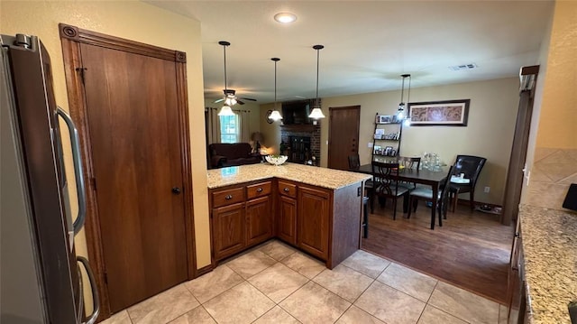 339770 E 1040th Cir, Meeker, OK 74855 - kitchen with ceiling fan, freestanding refrigerator, a fireplace, light tile patterned floors, and hanging light fixtures