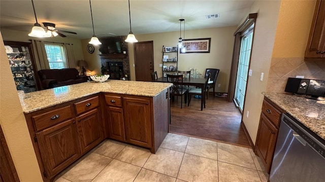339770 E 1040th Cir, Meeker, OK 74855 - kitchen featuring stainless steel dishwasher, a brick fireplace, light tile patterned floors, light stone counters, and pendant lighting