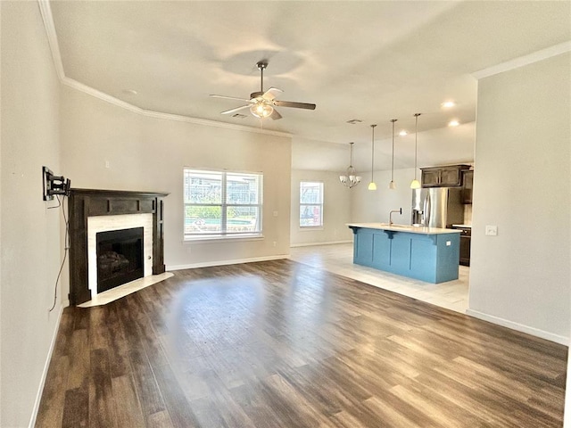 9632 Ashford Dr, Yukon, OK 73099 - unfurnished living room with ceiling fan, ornamental molding, a fireplace with flush hearth, wood finished floors, and a chandelier