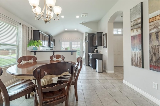 19005 Valencia Park Dr, Edmond, OK 73012 - dining area with arched walkways, a chandelier, lofted ceiling, baseboards, and light tile patterned floors
