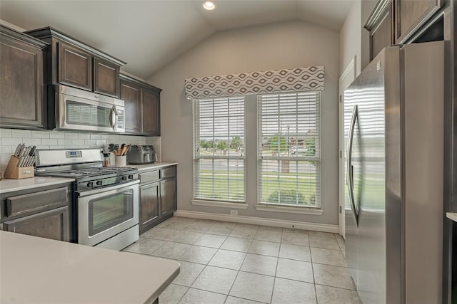 19005 Valencia Park Dr, Edmond, OK 73012 - kitchen featuring appliances with stainless steel finishes, vaulted ceiling, dark brown cabinetry, light countertops, and baseboards