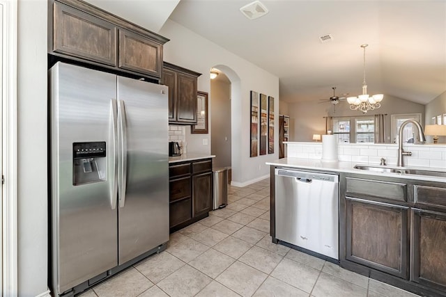 19005 Valencia Park Dr, Edmond, OK 73012 - kitchen featuring appliances with stainless steel finishes, a sink, dark brown cabinets, decorative backsplash, and arched walkways