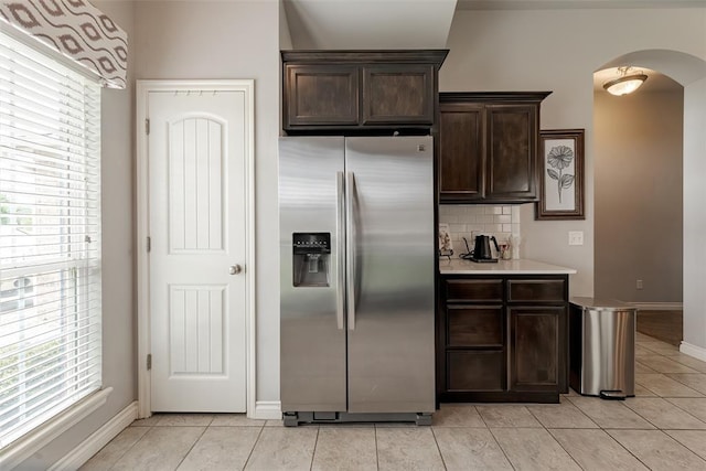 19005 Valencia Park Dr, Edmond, OK 73012 - kitchen featuring stainless steel fridge with ice dispenser, arched walkways, plenty of natural light, and dark brown cabinetry