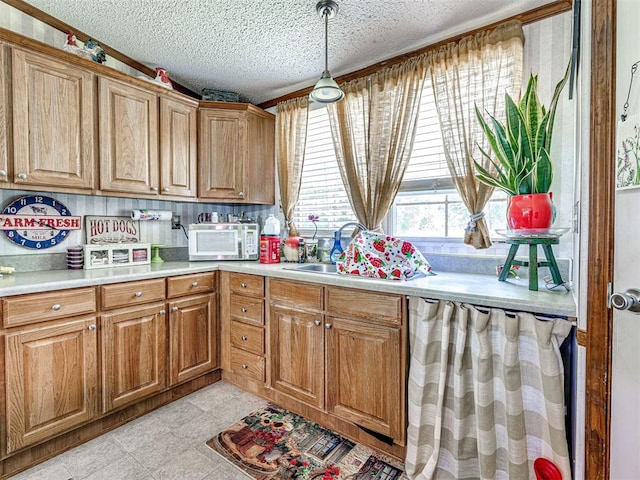 19519 N 2730th Rd, Kingfisher, OK 73750 - kitchen featuring white microwave, light countertops, brown cabinetry, pendant lighting, and a textured ceiling