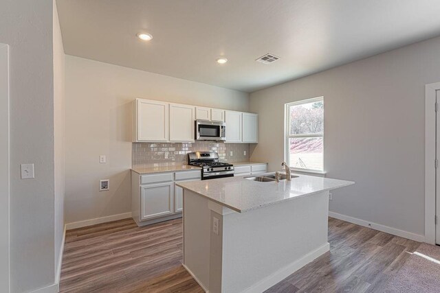 741 Stella Trl, Guthrie, OK 73044 - kitchen featuring stainless steel appliances, a sink, white cabinetry, tasteful backsplash, and wood finished floors