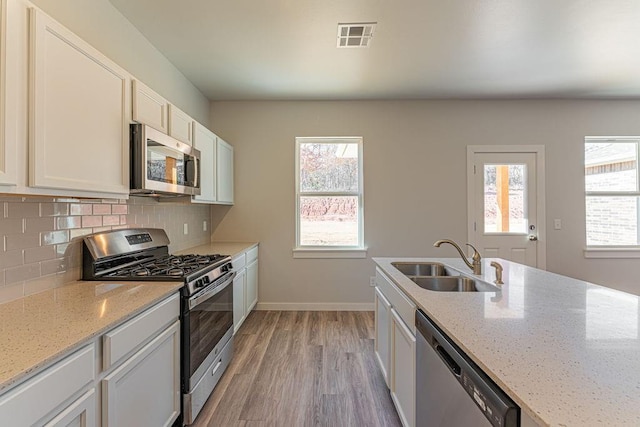 741 Stella Trl, Guthrie, OK 73044 - kitchen with appliances with stainless steel finishes, a sink, light wood-style flooring, decorative backsplash, and baseboards