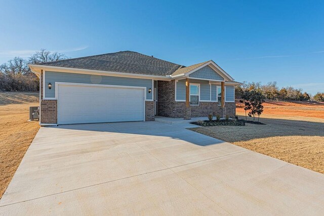 741 Stella Trl, Guthrie, OK 73044 - view of front of home featuring brick siding, concrete driveway, a garage, and a front yard