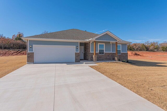 741 Stella Trl, Guthrie, OK 73044 - view of front facade with brick siding, driveway, an attached garage, and a front yard
