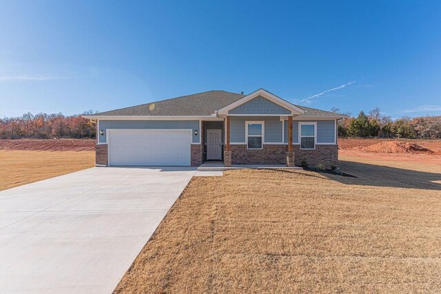 741 Stella Trl, Guthrie, OK 73044 - craftsman house featuring a garage, brick siding, concrete driveway, and a front lawn