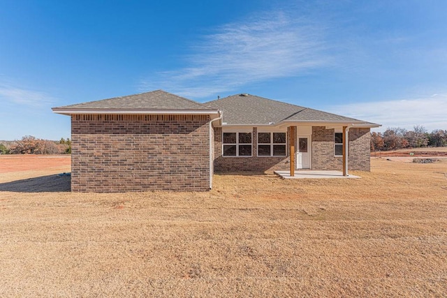 741 Stella Trl, Guthrie, OK 73044 - rear view of house featuring a patio area, brick siding, roof with shingles, and a lawn