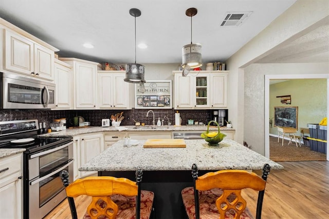 26114 State Highway 19, Cyril, OK 73029 - kitchen featuring stainless steel appliances, a sink, a breakfast bar, backsplash, and light wood-style flooring
