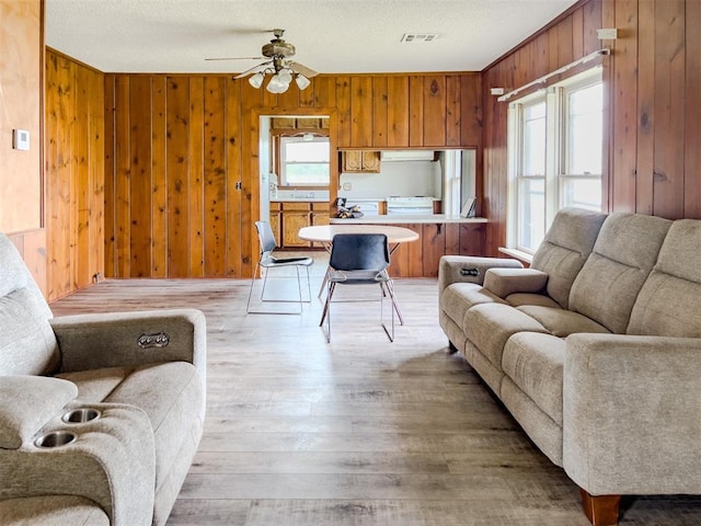 8701 Cornforth Rd, Guthrie, OK 73044 - living area featuring plenty of natural light, wood walls, ceiling fan, and light wood finished floors