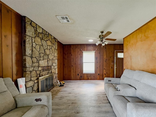 8701 Cornforth Rd, Guthrie, OK 73044 - living area with wood finished floors, ceiling fan, a textured ceiling, a fireplace, and wooden walls