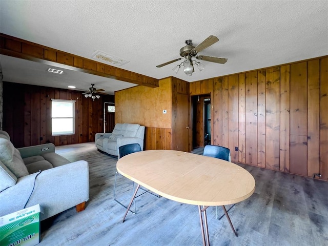 8701 Cornforth Rd, Guthrie, OK 73044 - living area featuring a ceiling fan, wood finished floors, wooden walls, and a textured ceiling